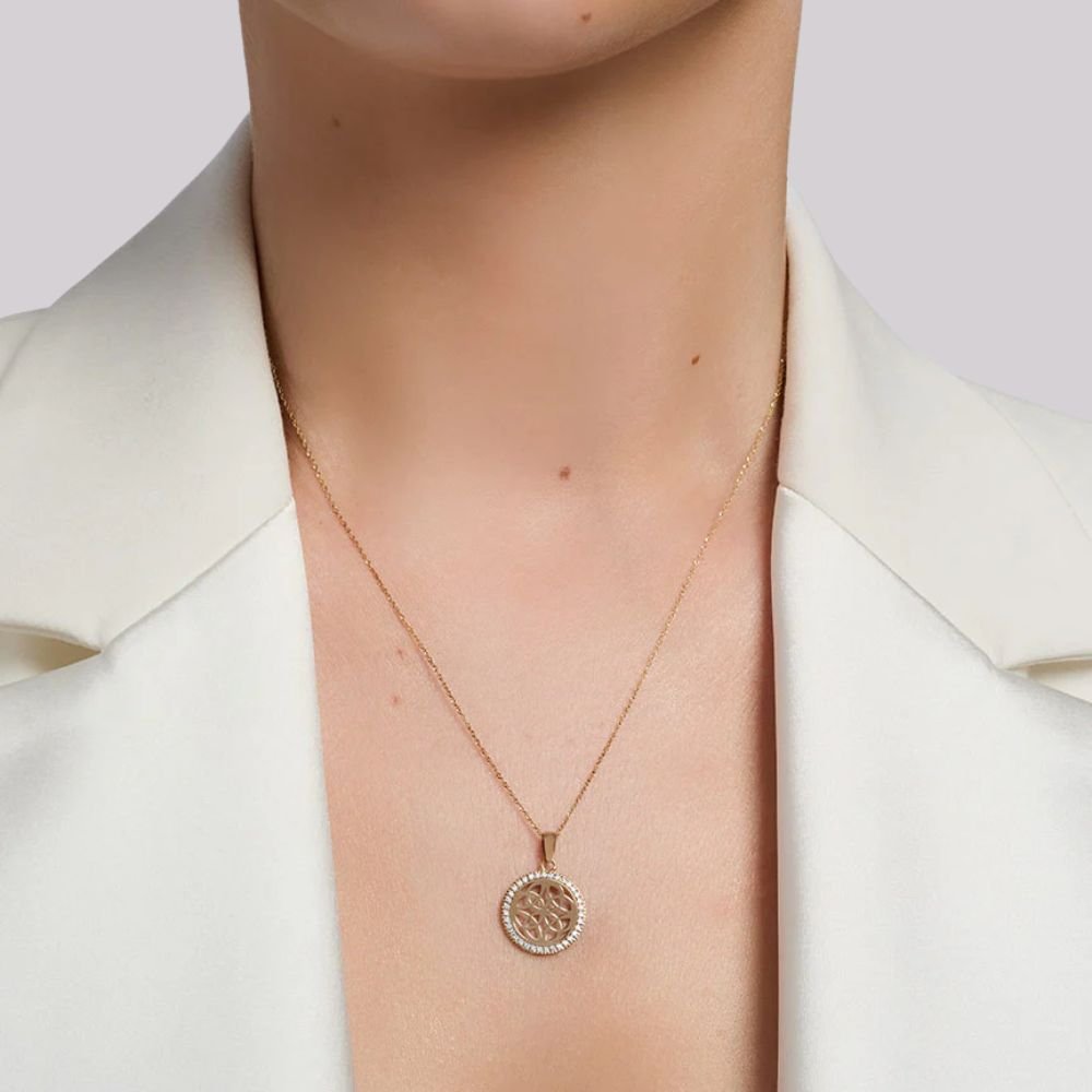 Necklace with a pendant worn by a person in a white blazer
