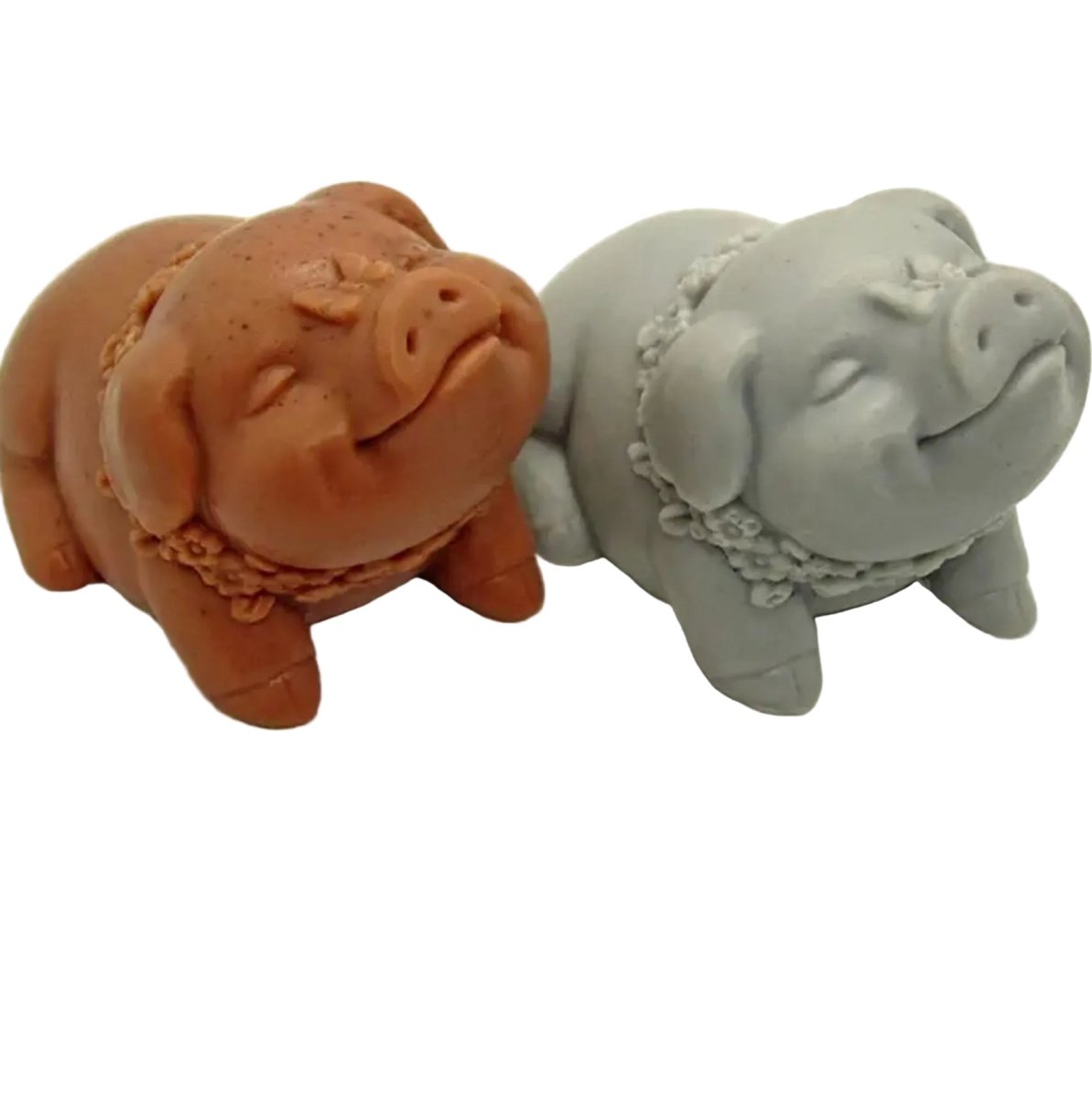 Two pig-shaped candles, one brown and one gray, on a white background.
