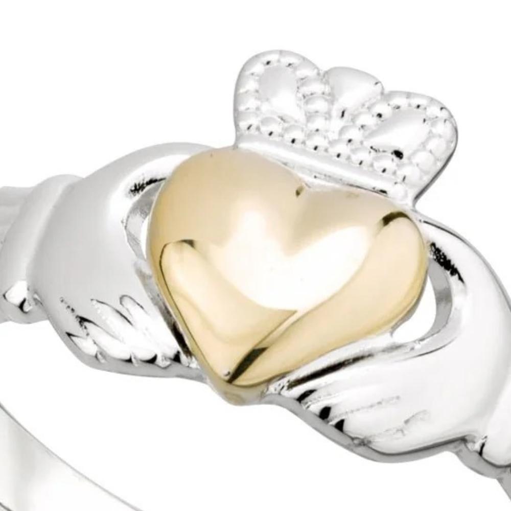 Gold heart charm on a silver claddagh ring with a white background
