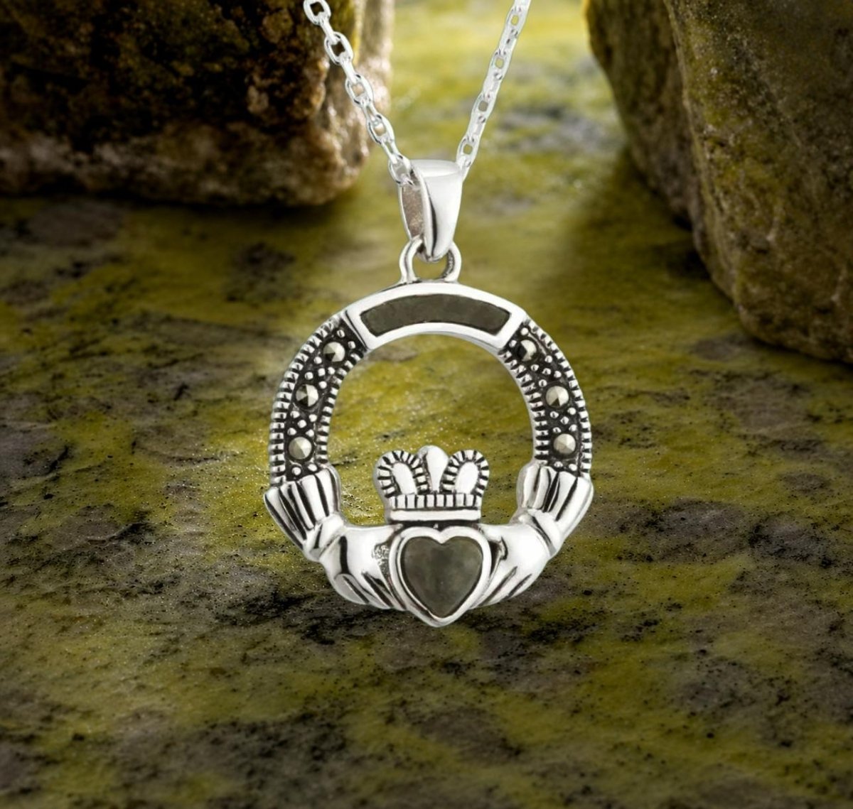 Silver Claddagh pendant on a chain against a stone background