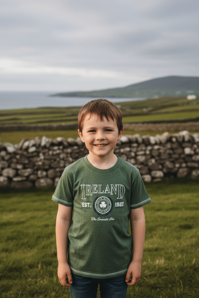 Smiling child wearing green Ireland Collegiate T-shirt with shamrock crest Est. 1922 in rural Irish field beside wall