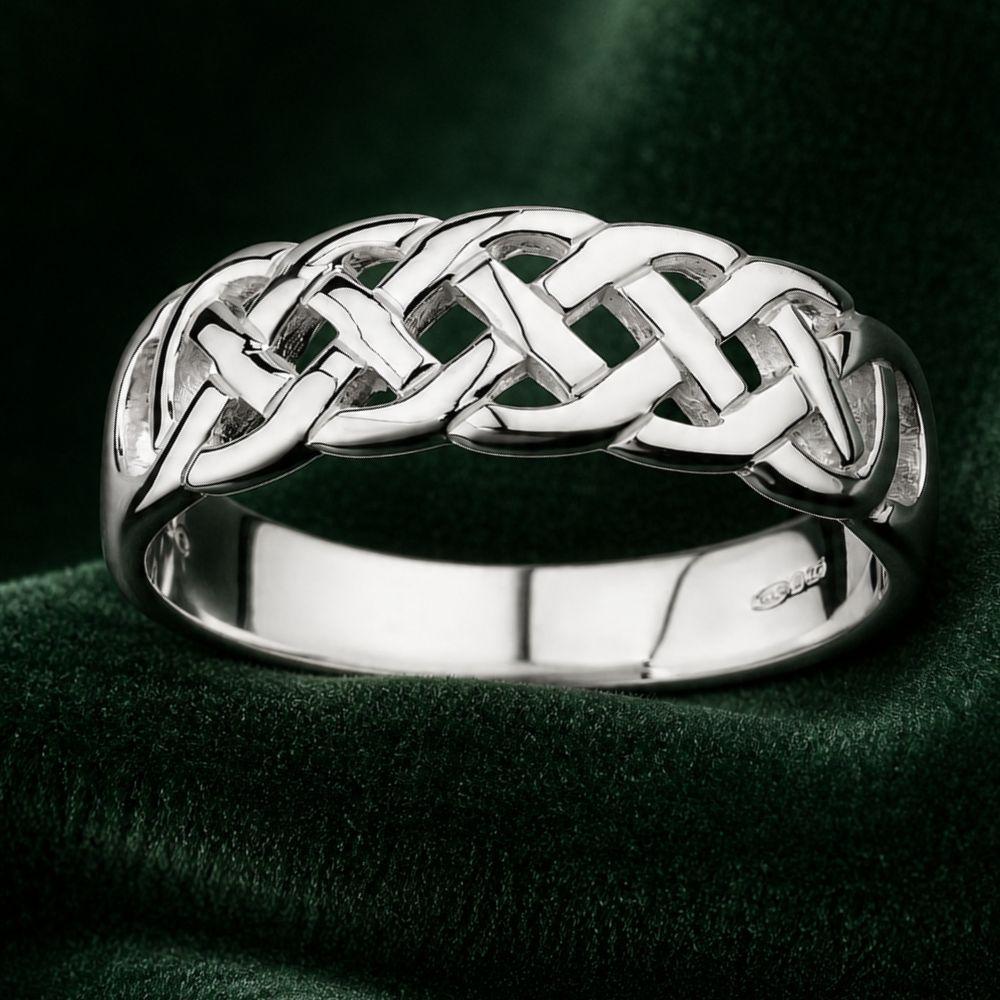 Silver Celtic knot ring on a dark green fabric background