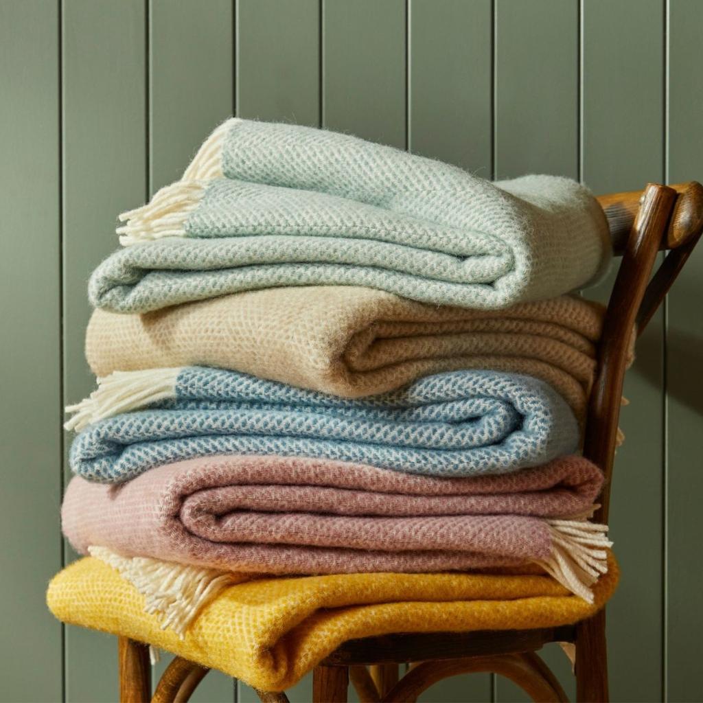 Tweedmill Beehive Ocean Wool Throw in ocean blues, folded on a chair, showcasing beehive weave.