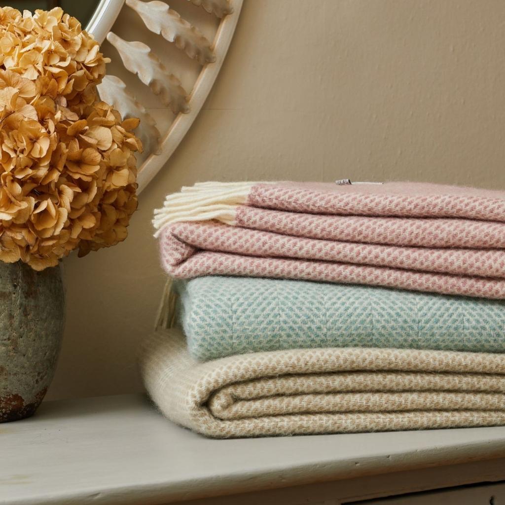 Tweedmill Beehive Ocean wool throw stacked in pastel pink, blue, beige with dried hydrangea vase.