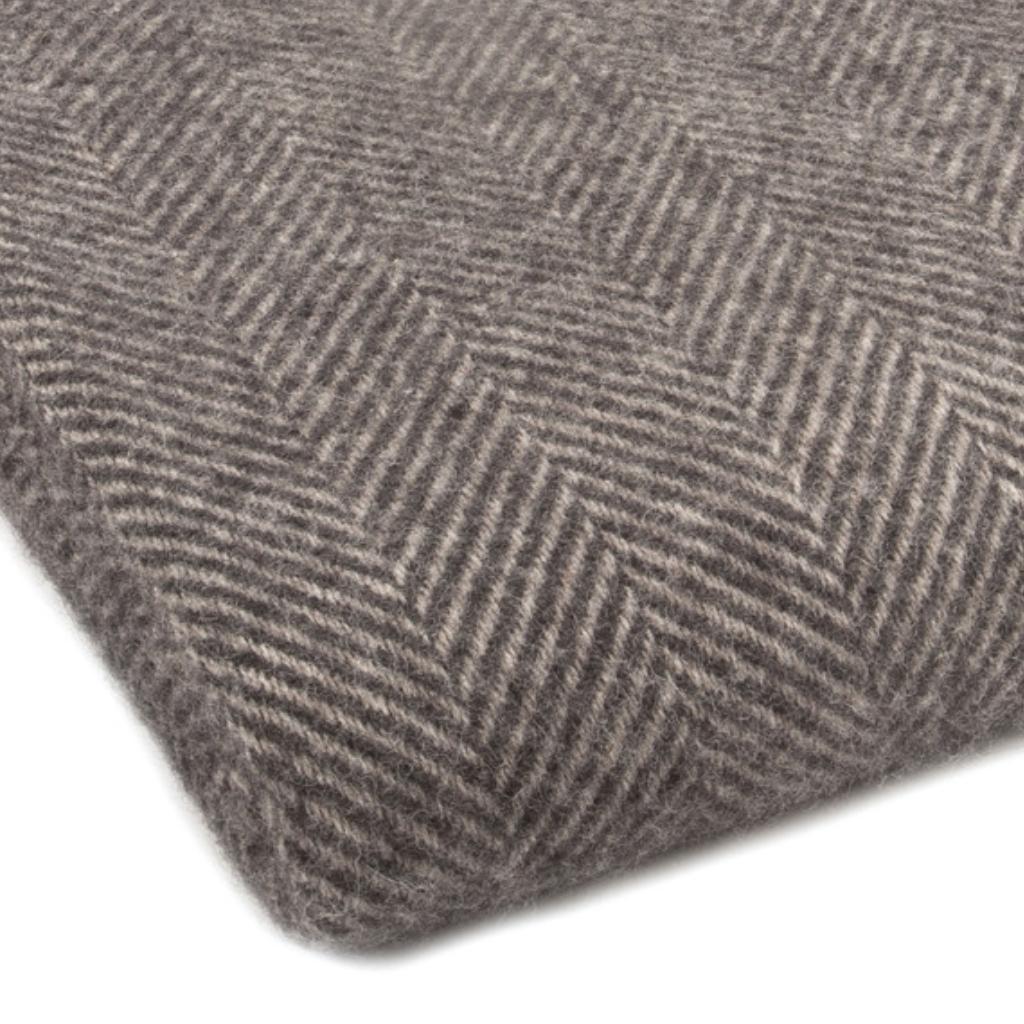 A close-up of a gray and beige herringbone woven fabric, showing the texture and pattern of the material.